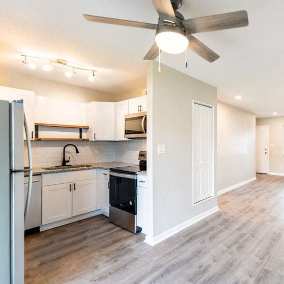 a kitchen with a refrigerator, sink, and stove.