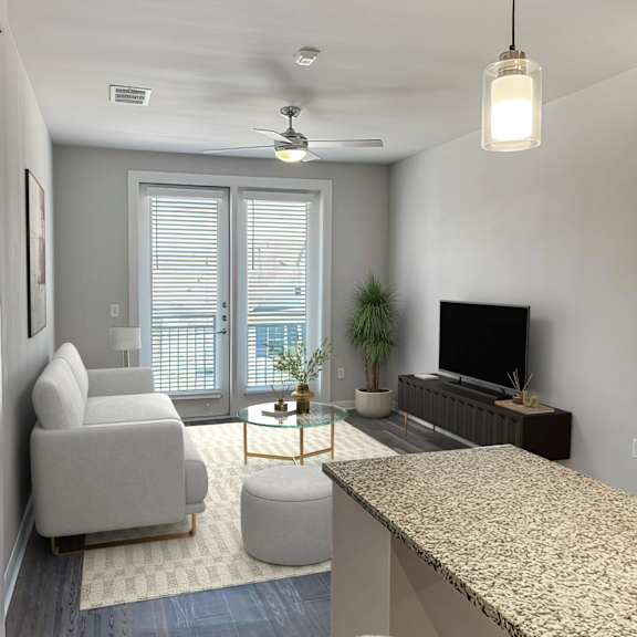 Thumbnail 3 of 5 A living room with a grey couch, a white ottoman, a television, and a ceiling fan.
