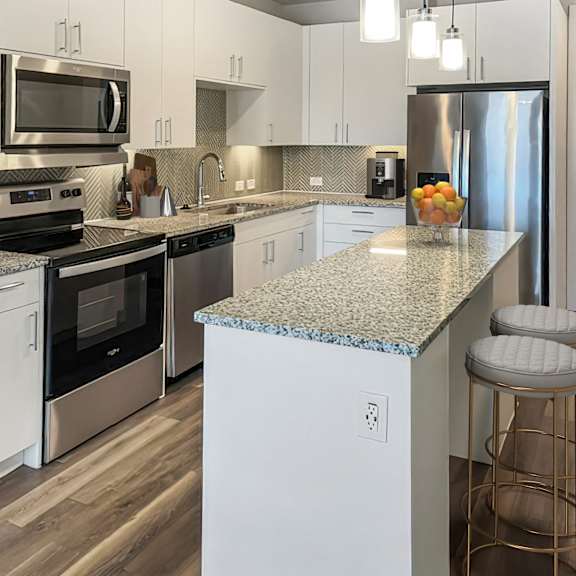 Thumbnail 4 of 5 A kitchen with a granite countertop and stainless steel appliances.