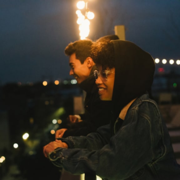 two people standing on a balcony at night