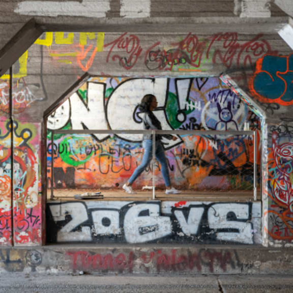 a woman walking on a sidewalk in front of a graffiti covered wall