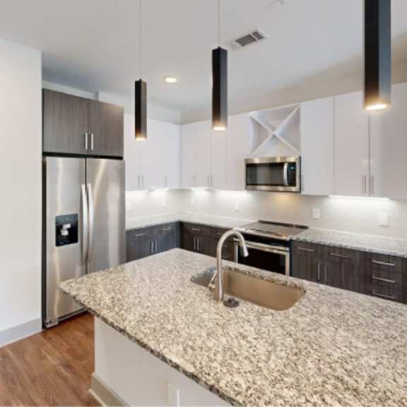 Thumbnail 2 of 11 A kitchen with a granite countertop and a sink.