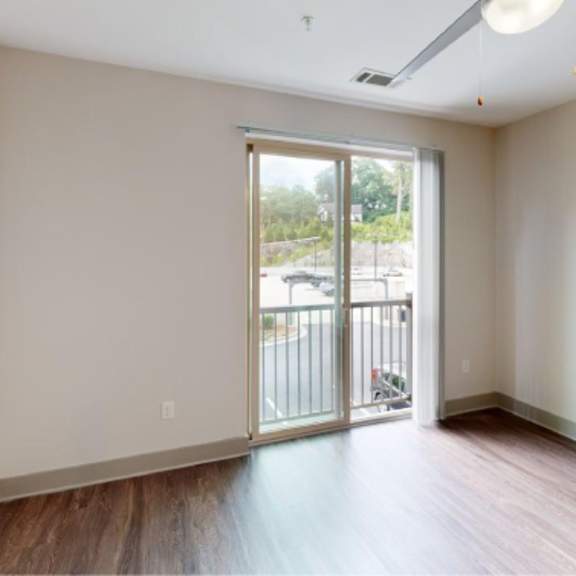 Thumbnail 9 of 11 A room with a sliding glass door leading to a balcony.