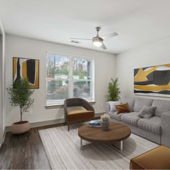 Thumbnail 3 of 9 A living room with a grey couch, a brown coffee table, and a ceiling fan.