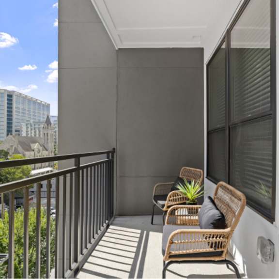 Thumbnail 4 of 4 A balcony with two chairs and a table with a plant on it.