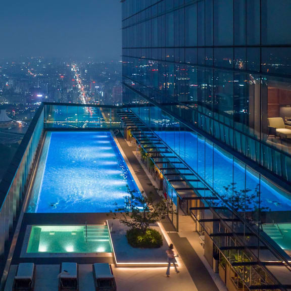 A long, illuminated swimming pool is lit up at night.