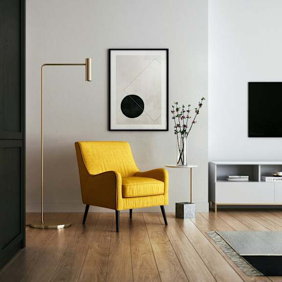 a yellow chair in a living room with a lamp and a television