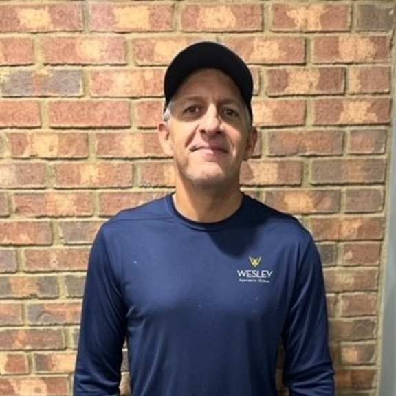a man standing in front of a brick wall