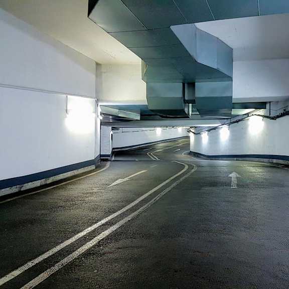 a long, narrow parking garage with white lines on the ground.