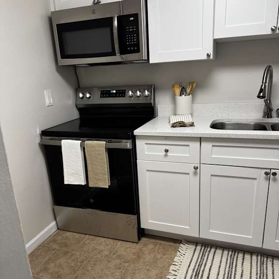 a kitchen with white cabinets and a black stove top oven.