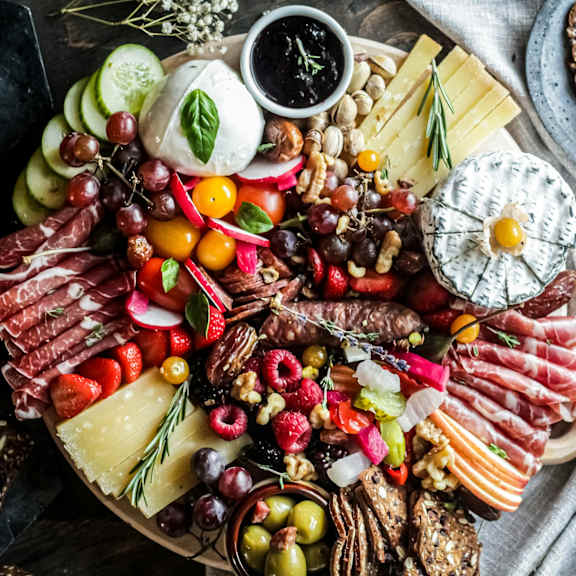 Thumbnail 4 of 4 A variety of cheeses, meats, and fruits are arranged on a platter.