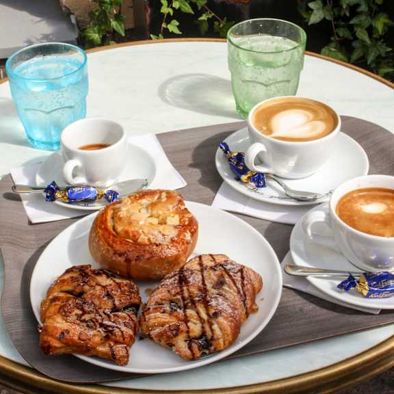 Thumbnail 3 of 4 A table with a plate of food and two cups of coffee.