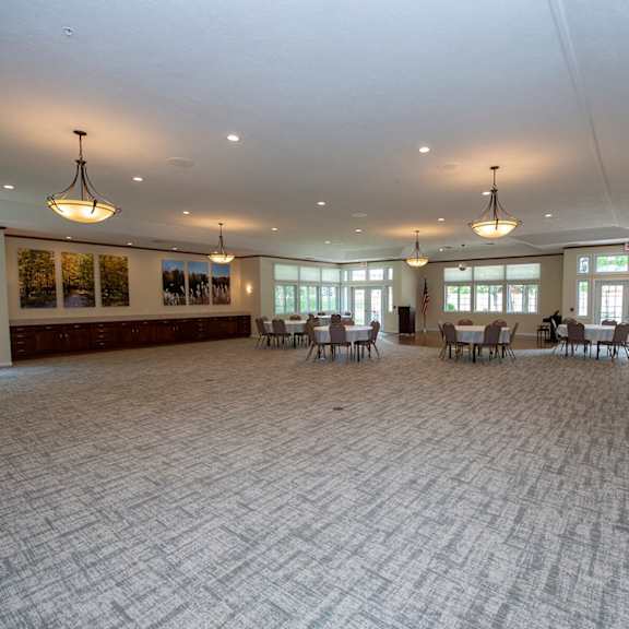 a large room with a carpeted floor and a few chairs and tables.