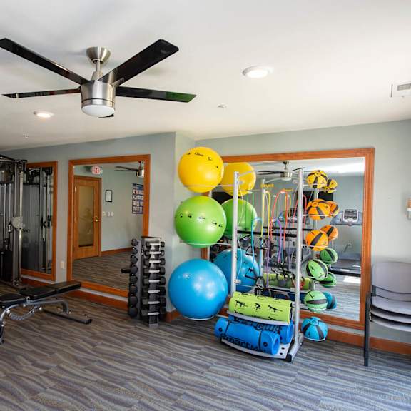 a gym with a variety of equipment including weights, a bench, and a mirror.
