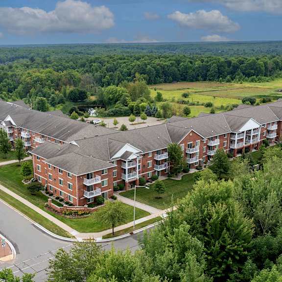 an aerial view of a large apartment complex with a green field in the background