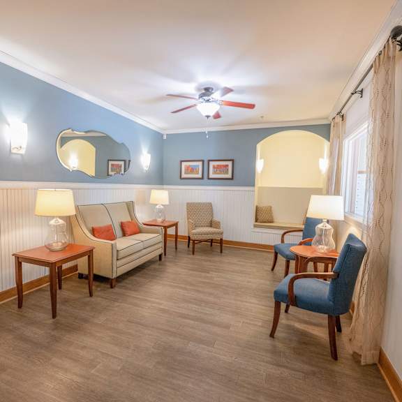 a living room with a sofa, chairs, and a ceiling fan.