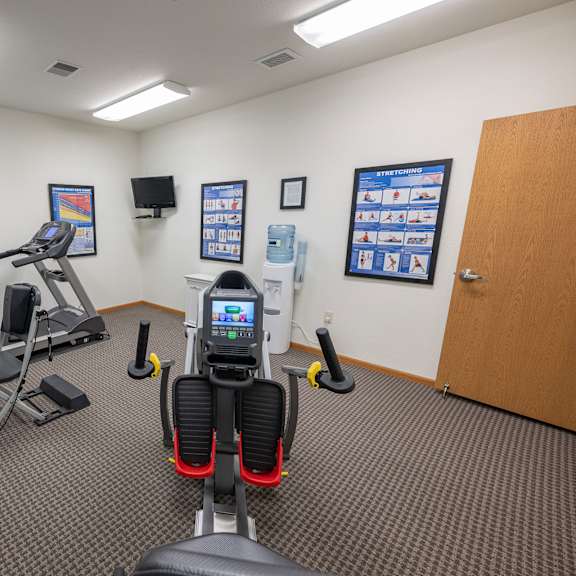 a gym room with a treadmill, exercise bike, and other equipment.