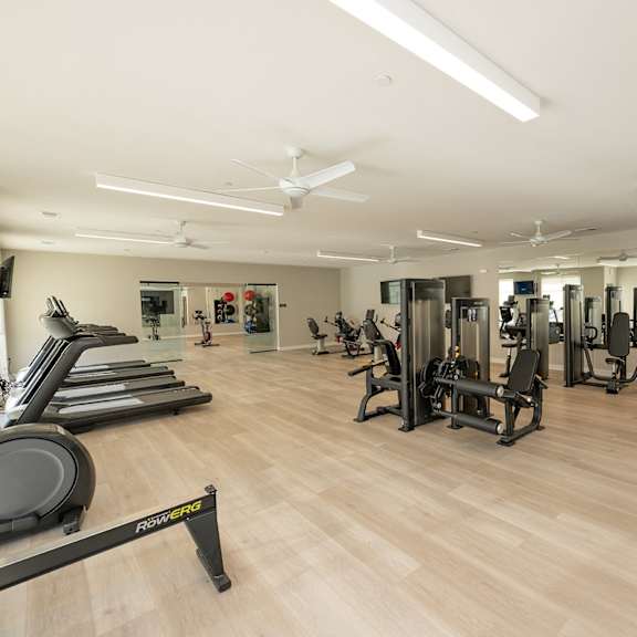 a gym with cardio equipment and weights on a wooden floor