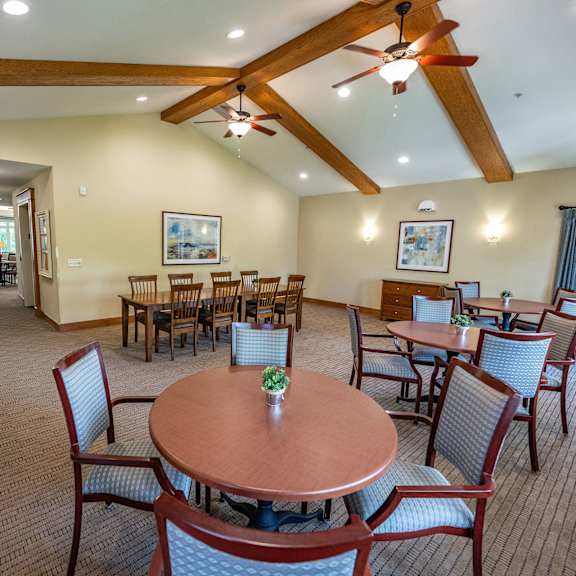 a room with a brown table and chairs and a ceiling fan.