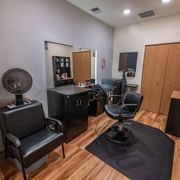 a room with a black chair and a black table with a fan on it.