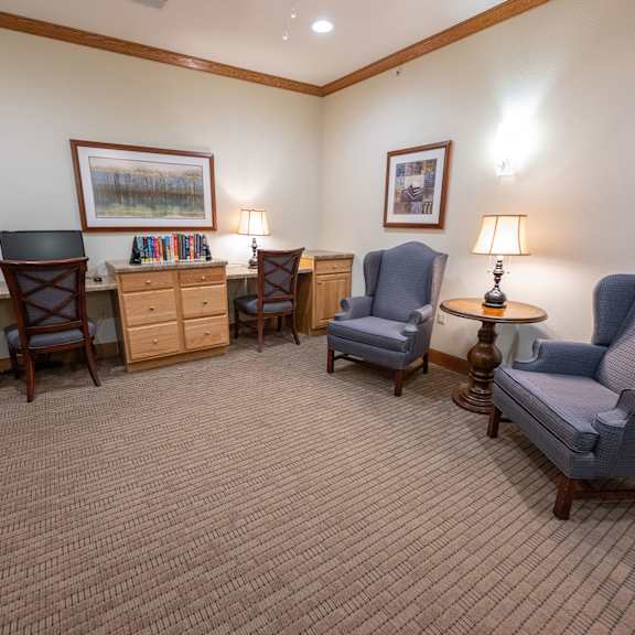 a room with a carpeted floor and a variety of chairs and tables.