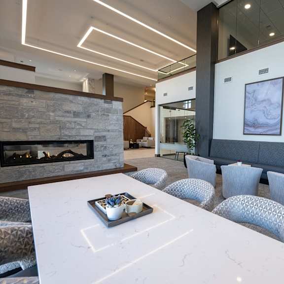 a  lobby area with a fireplace and a white marble coffee table with seating.