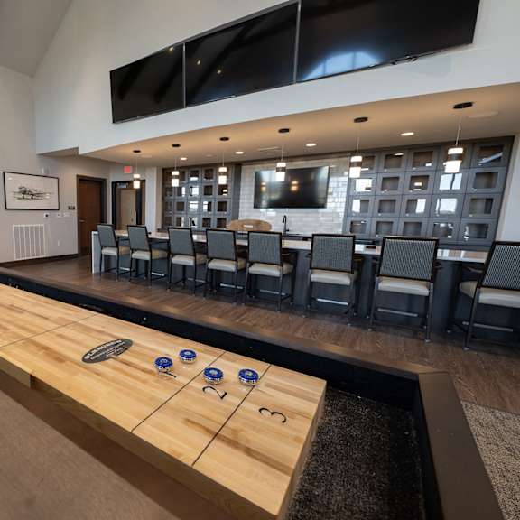a shuffleboard table in the center of a large room with chairs and a television