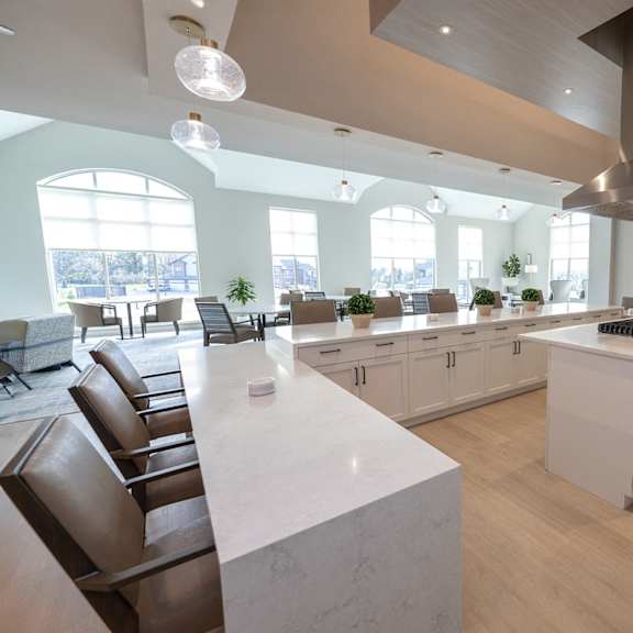 a modern kitchen with a large island and brown chairs.