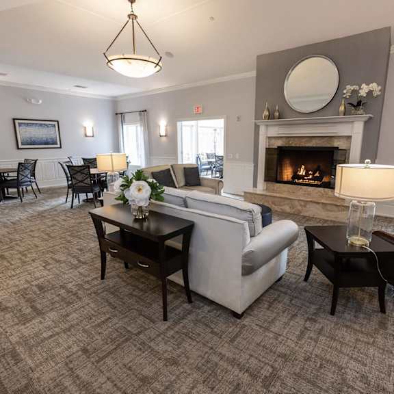 a living room with a fireplace and a dining room in the background