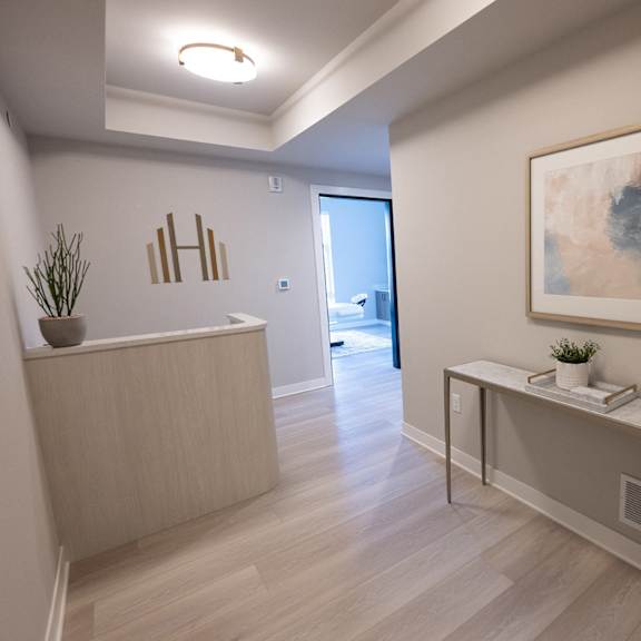 a hallway with a reception desk and a painting on the wall.
