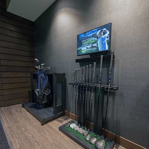 a golf-simulator room showing a view of a rack of golf clubs.