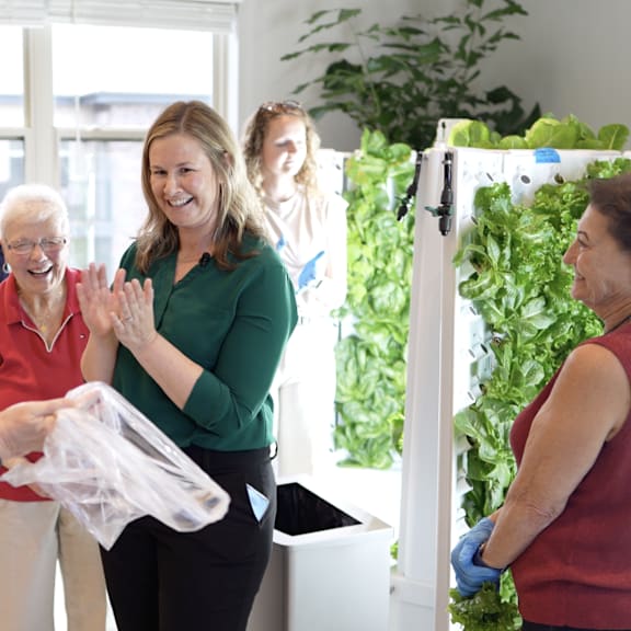a woman in a green shirt is handing a plastic bag to an elderly woman in a red shirt.