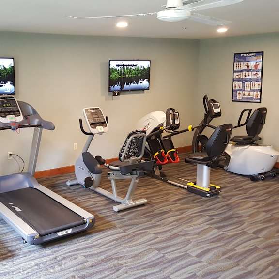 a gym with treadmills, elliptical machines, and other exercise equipment.