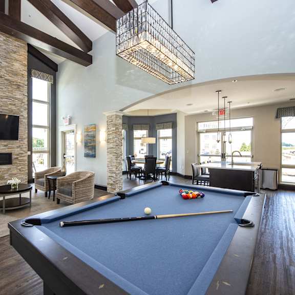 a pool table is in the middle of a room with a stone fireplace and a television above it.