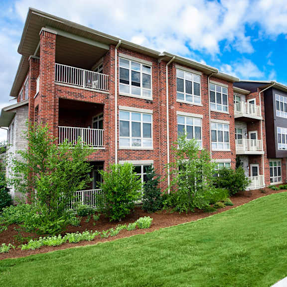 an apartment building with green grass and a sidewalk