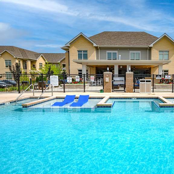 a large swimming pool with blue chairs in front of a house