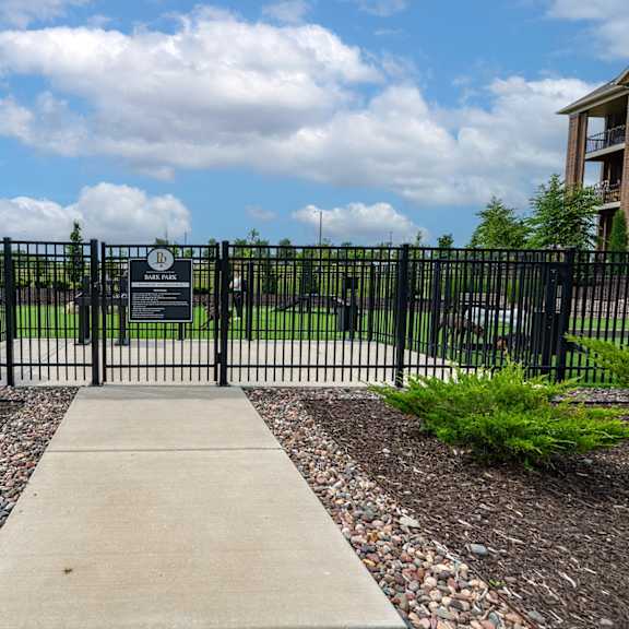 a black gate with a sign on it in front of a park