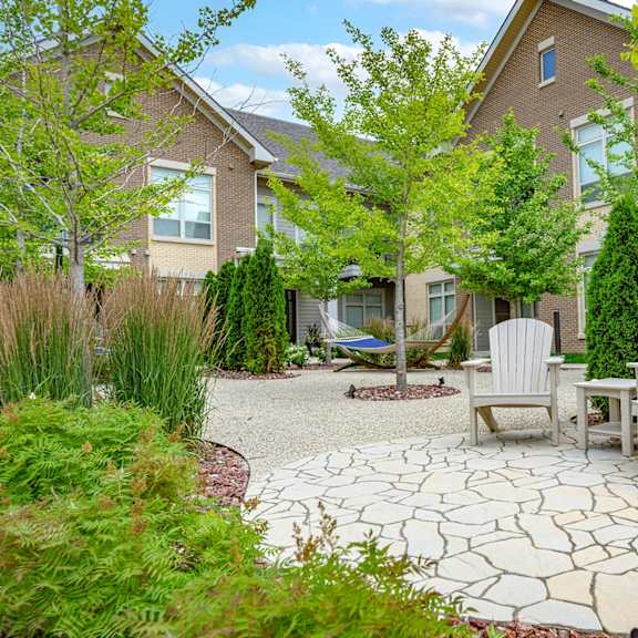 a patio with two chairs and a table in front of a house