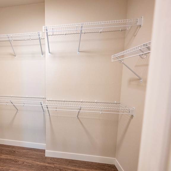 a spacious walk in closet with empty shelves and a wood floor