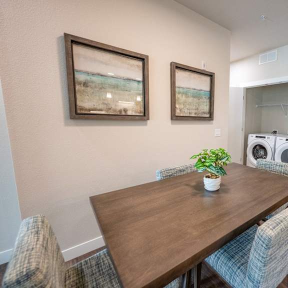a dining room with a table and chairs and a washing machine in a laundry room