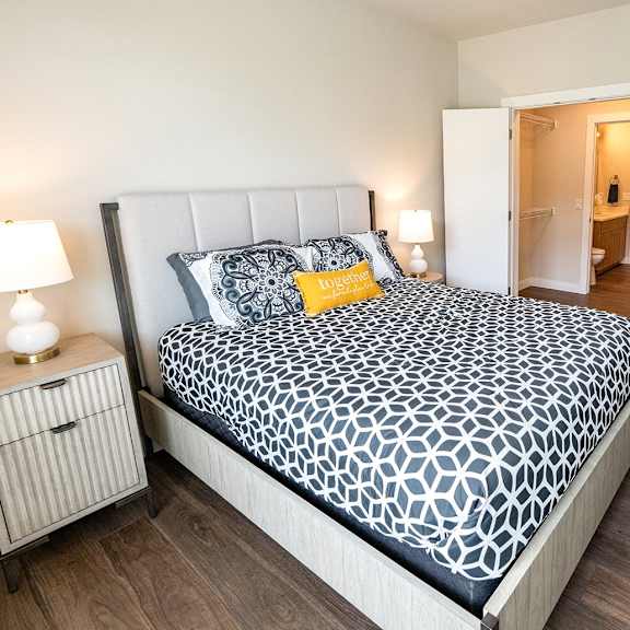 a bedroom with a large bed and a view of the living room of a apartment