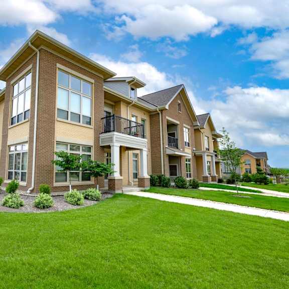 a row of townhomes with green grass and a blue sky