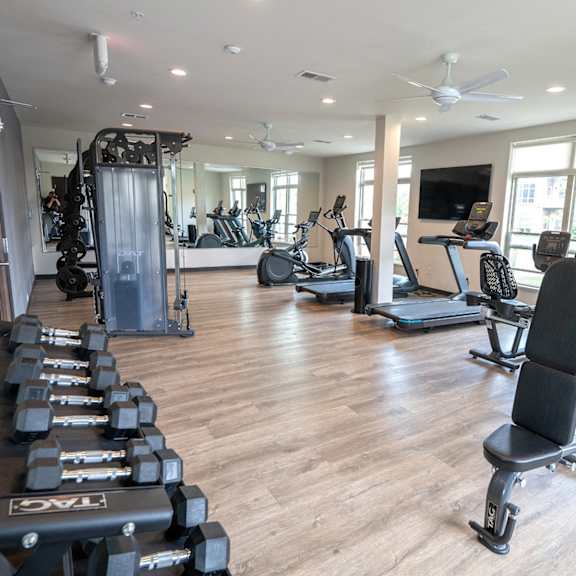 a gym with cardio machines and weights on a wooden floor