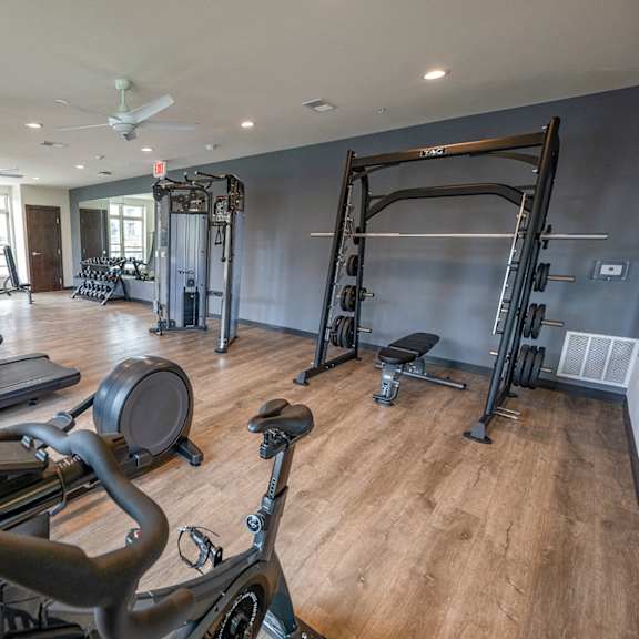 a gym with cardio equipment and weights on a wooden floor