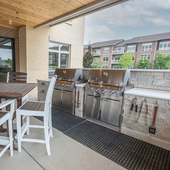 a patio with tables and chairs and barbecue grills