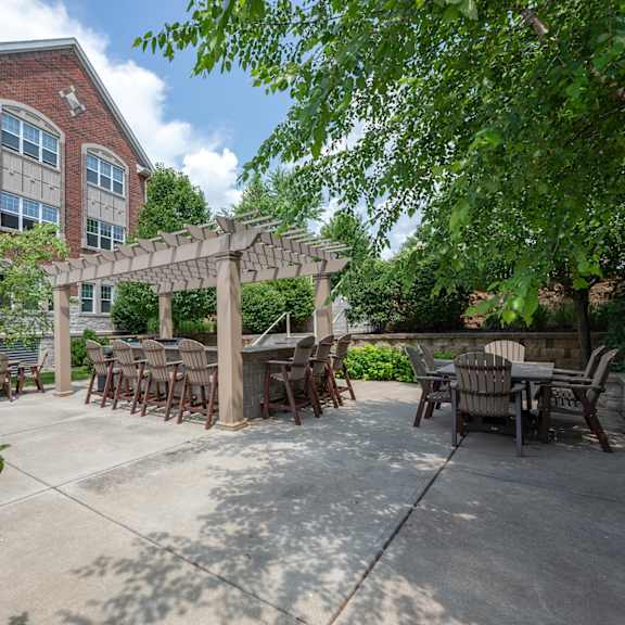 a patio with tables and chairs and a pergola in front of a building