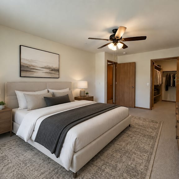 a bedroom with a large bed, a ceiling fan, and a painting on the wall.