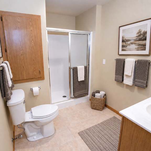 a bathroom with a toilet, sink, and shower.