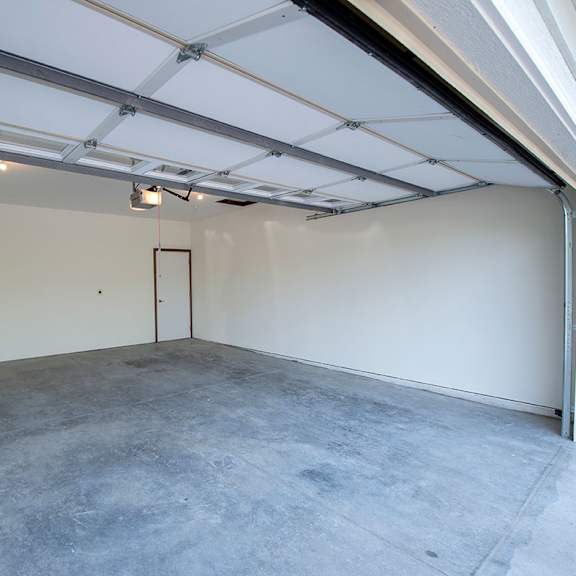 a large empty garage with a concrete floor and white walls.