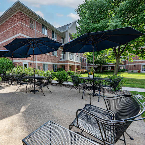 a patio area with black chairs and umbrellas in front of a brick building.